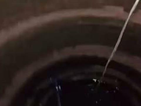 Poço caipira visto de cima, com os anéis de concreto e a água no fundo