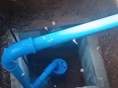 Caixa de concreto com a bomba submersa ligada ao cano azul que leva a água do poço