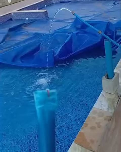 Piscina sendo enchida com a água do poço por um cano azul