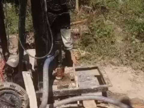 Perfuratriz trabalhando no terreno, com a mangueira de água ligada à sonda